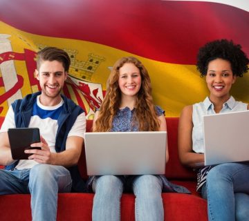 Students studying with laptops in front of Spanish flag