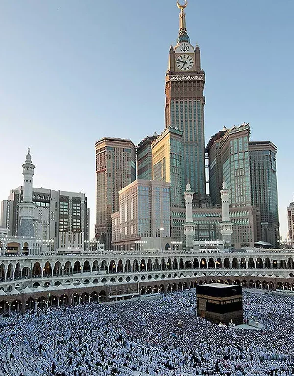 Kaaba surrounded by pilgrims in Mecca with Abraj Al Bait Towers in the background.