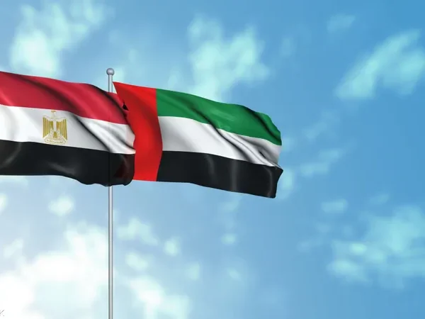 Egyptian and UAE flags waving against a blue sky.