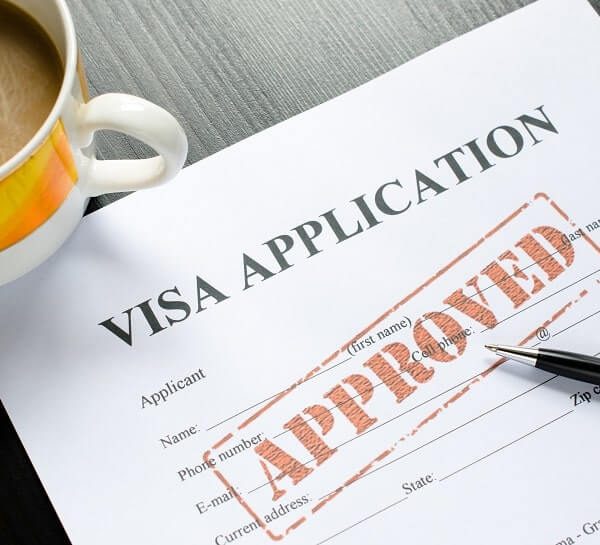 Visa application form with approved stamp and pen.